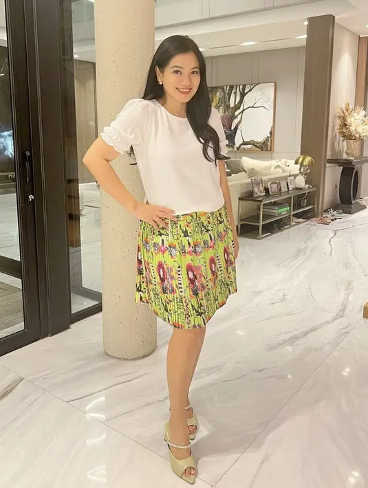 <p>Mengenakan atasan putih lengan kerut, Titi Kamal memadukannya dengan mini skirt plisket warna hijau bermotif. Semakin feminim dengan heels warna sagenya. (@titi_kamall)</p>