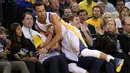 Stephen Curry #30 terjatuh menindih fans Golden State Warriors lsaat melawan Portland Trail Blazers  pada laga NBA Playoffs di ORACLE Arena,Oakland, California,(3/4/2016). (Ezra Shaw/Getty Images/AFP)
