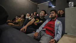 Relawan bisik menjelaskan alur cerita kepada penyandang tunanetra saat menyaksikan film di Bioskop Bisik di Pavilliun 28, Jakarta, Minggu (14/1). Hal ini membuat menonton bioskop bukan menjadi hal mustahil lagi bagi tunanetra. (Liputan6.com/Faizal Fanani)