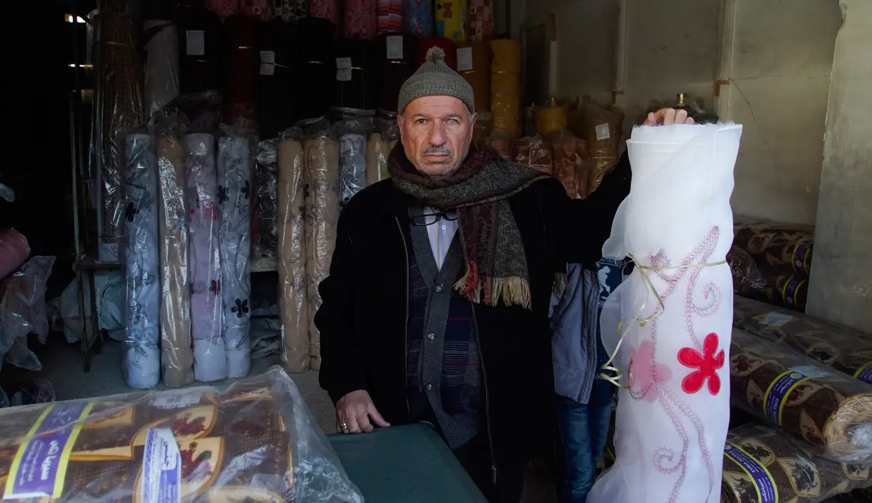 Seorang pedagang tekstil, Mahmoud Mimeh berpose di dalam tokonya di kota tua Aleppo, Suriah (21/1). Banyak bangunan kuno di Kota Tua ini yang hancur akibat bentrokan antara tentara Suriah dan pasukan pemberontak. (AP Photo / Mstyslav Chernov)