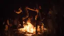 Peserta ritual melompat diatas api unggun saat mengikuti upacara ritual pagan kuno di dekat desa Glubokovo, Rusia (24/6). (AFP Photo/Andrei Borodulin)