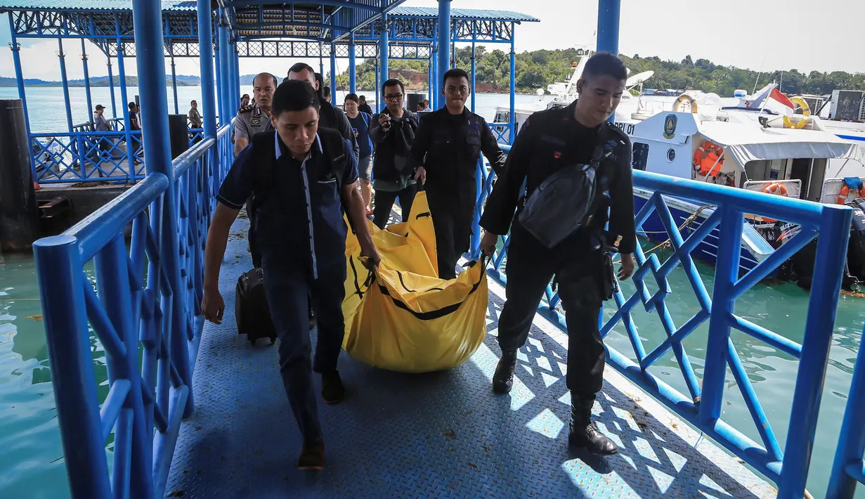 Anggota kepolisian mengangkat kantong jenazah yang berisikan puing-puing dan barang-barang dari jatuhnya pesawat jenis M-28 Skytrcuk milik Polri di Pelabuhan Telaga Punggur, Batam, Kepulauan Riau, Minggu (4/12). (Antara Foto/M N Kanwa/via REUTERS)