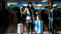Seorang penumpang berjalan dengan kopernya di aula kedatangan di Bandara Internasional Haneda Tokyo, Jumat (18/2/2022). Pemerintah Jepang mengumumkan rencana untuk melonggarkan aturan perbatasan virus bagi pekerja dan pelajar. (AFP/Philip Fong)