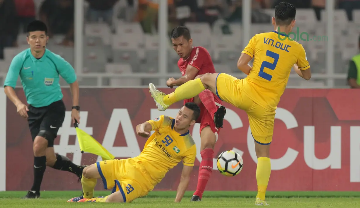 Kapten Persija Jakarta, Ismed Sofyan (tengah) melepaskan tembakan melewati adangan dua pemain Song Lam Nghe An FC pada laga Piala AFC 2018 di Stadion Utama GBK, Senayan, Jakarta, (13/3/2018). Persija Jakarta menang 1-0. (Bola.com/Nick Hanoatubun)