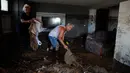 Orang-orang mencoba membersihkan puing-puing dari rumah setelah badai dan hujan lebat yang menyebabkan banjir pulau Evia, Yunani, Senin (10/8/2020). Satu orang masih hilang, sementara banjir memblokir jalan serta merusak rumah-rumah di pulau di timur laut Athena itu. (AP Photo/Thanassis Stavrakis)