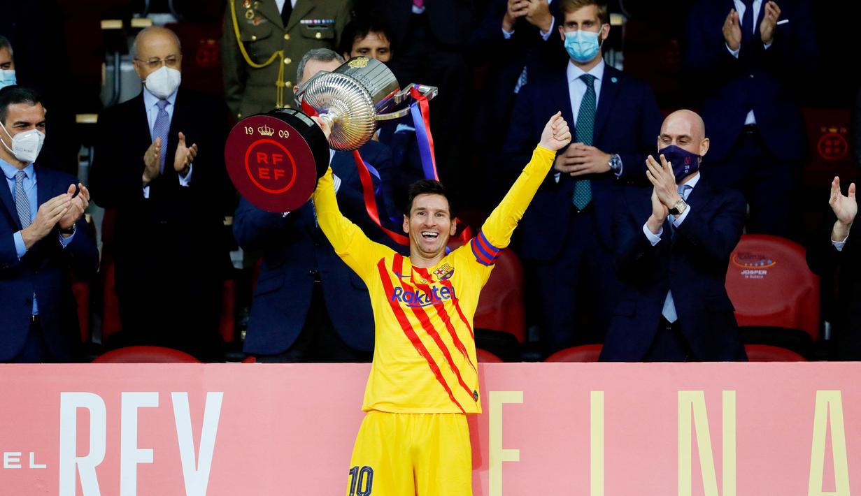 Striker Barcelona, Lionel Messi, mengangkat trofi usai menjuarai Copa del Rey di Stadion Olimpico de Sevilla, Minggu (18/4/2021). Barcelona menang 4-0 atas Athletic Bilbao. (AFP/Cristina Quicler)