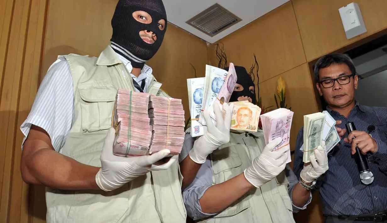 Petugas memperlihatkan barang bukti berupa mata uang dollar AS dan dollar Singapura yang ditemukan dalam operasi tangkap tangan terhadap Gubernur Riau Annas Maamun, Jakarta, (26/9/14). (Liputan6.com/Miftahul Hayat) 