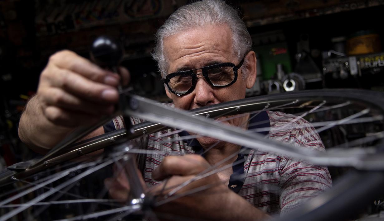 Raffaello Bianco, mekanik dan pecinta sepeda memperbaiki roda di bengkel mekaniknya di ruang bawah tanah apartemennya di Turin, Italia, 7 Juli 2020. Sepanjang hidupnya Bianco bekerja sebagai dokter hewan, tetapi ia mengatakan sepeda selalu memiliki gairah yang lebih besar. (MARCO BERTORELLO/AFP)