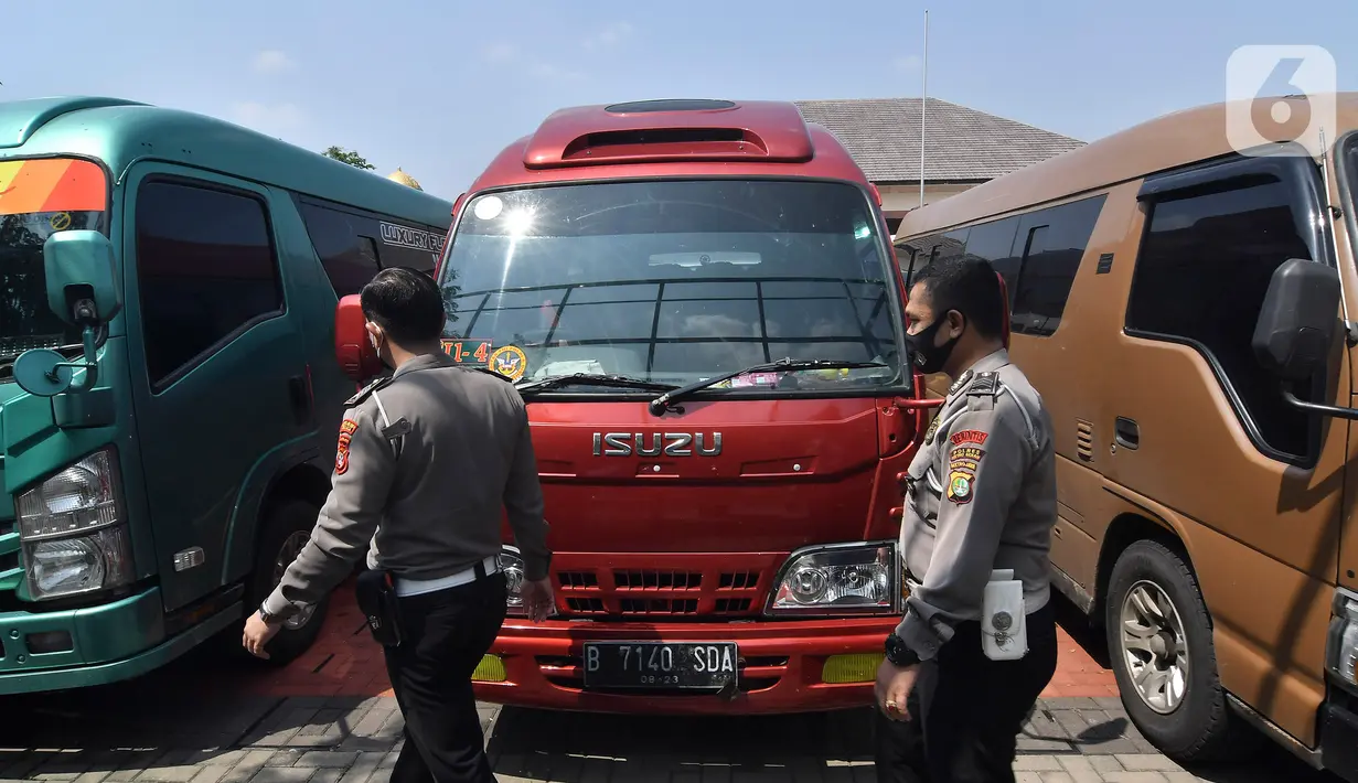 Petugas polisi memeriksa mobil travel gelap yang disita di halaman Polres Metro Kabupaten Bekasi, Jawa Barat, Senin (10/5/2021). Satlantas Polres Metro Bekasi mengamankan 32 travel gelap yang masih beroperasi saat larangan mudik dari tanggal 6-17 Mei 2021. (Liputan6.com/Herman Zakharia)