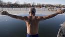 Seorang pria bersiap untuk melompat ke dalam danau Hou Hai yang beku di Beijing, China (24/1). (AFP Photo/Nicolas Asfouri)
