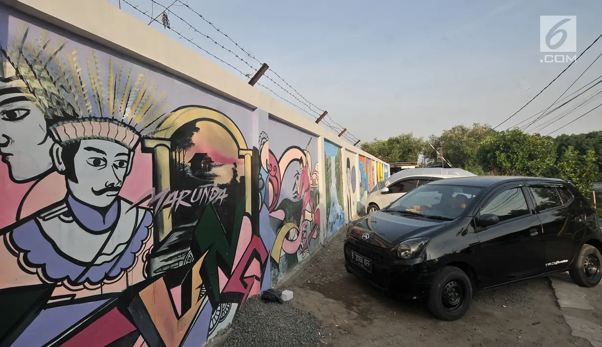 Mobil terparkir di dekat mural Betawi yang berada di Kampung Pitung, Marunda, Jakarta, Senin (2/7). Mural-mural bernuansa Betawi kini menghiasi destinasi wisata rumah dan masjid Pitung. (Merdeka.com/Iqbal S. Nugroho)