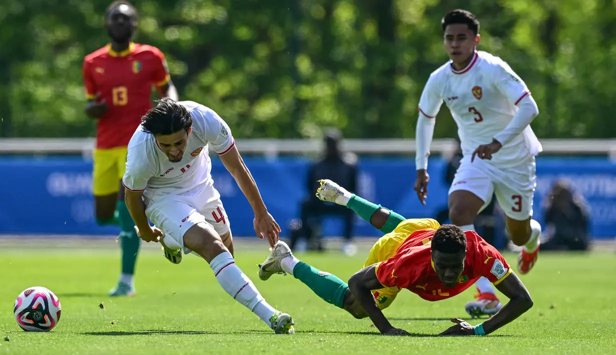 Bek Guinea U-23, Saidou Sow (kanan) terjatuh usai perebutan bola dengan bek Timnas Indonesia U-23. Nathan Tjoe-A-On pada laga play-off antar-konfederasi menuju Olimpiade Paris 2024 di Stade Pierre Pibarot, Centre National du Football de Clairefontaine, Prancis, Kamis (9/5/2024). (AFP/Miguel Medina)
