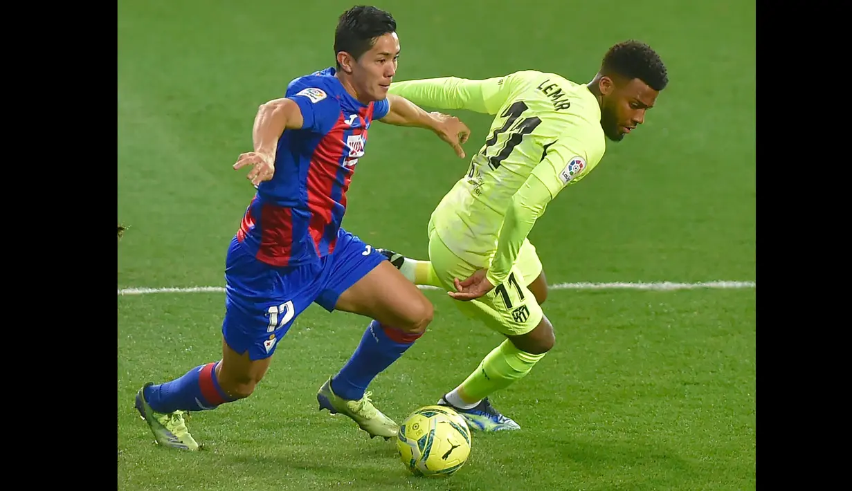 Pemain Eibar, Yoshinori Muto (kiri) berusaha melewati pemain Atletico Madrid, Thomas Lemar pada laga pekan ke-19 La Liga di Estadio Municipal de Ipurua, Jumat (23/1/2021). Atletico Madrid meraih kemenangan 2-1 atas Eibar. (Foto: AFP/Ander Gillenea)