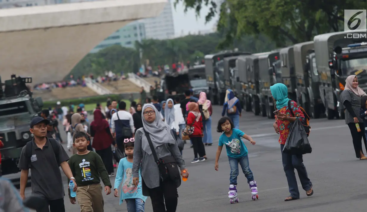 Warga bersama anak-anak berjalan-jalan di kawasan Monumen Nasional, Jakarta, Jumat (19/4). Libur panjang perayaan Paskah 2019 dimanfaatkan warga untuk berwisata di kawasan Monumen Nasional. (Liputan6.com/Helmi Fithriansyah)