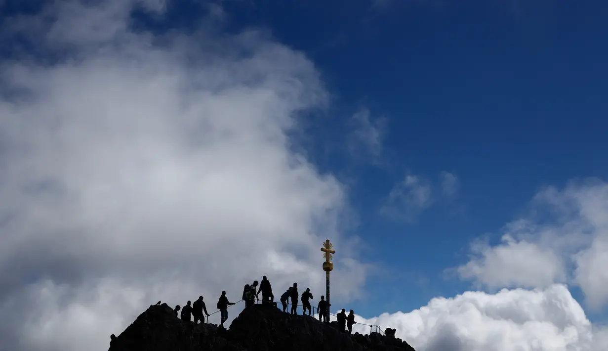 Orang-orang mengantre untuk mencapai puncak salib di puncak gunung tertinggi Jerman, Zugspitze, dekat Garmisch-Partenkirchen, Jerman pada 19 Agustus 2020. Setiap tahunnya gunung dengan ketinggian 2.962 meter tersebut membuat sekitar setengah juta pengunjung terpesona. (AP Photo/Matthias Schrader)