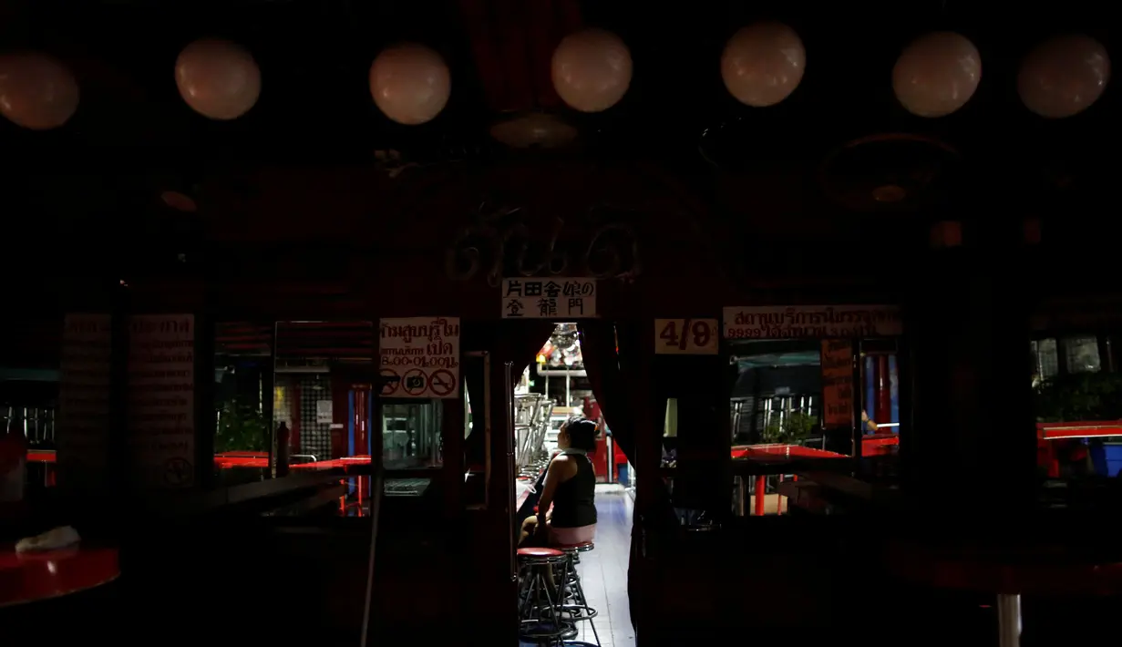 Seorang wanita berada di tempat hiburan malam yang tutup di sebuah kawasan prostitusi atau red-light district, Bangkok, Thailand, (17/10). Beberapa acara di Thailand banyak yang dibatalkan selama masa berkabung. (REUTERS/Issei Kato)