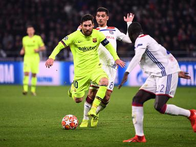 Aksi Lionel Messi mencoba melewat dua pemain Lyon pada leg 1, babak 16 besar Liga Champions yang berlangsung di stadion Parc Olympique Lyonnais, Lyon, Rabu (20/2). Barcelona bermain imbang 0-0 kontra Lyon. (AFP/Franck Fife)