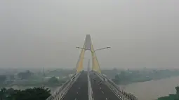 Gambar udara menunjukkan sebuah jembatan ketika kabut asap pekat menyelimuti Pekanbaru, Riau, Minggu (15/9/2019). Kabut asap yang menyelimuti Kota Pekanbaru makin pekat akibat kebakaran hutan dan lahan di Riau, Jambi, serta Sumatera Selatan. (ADEK BERRY/AFP)