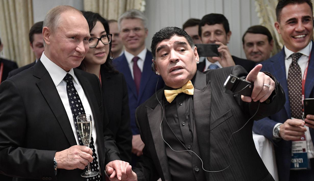 Legenda sepak bola, Diego Maradona berbincang dengan Presiden Rusia, Vladimir Putin, saat menghadiri Drawing Piala Dunia 2018 di Kremlin Palace, Jumat (1/12/2017). Acara tersebut dihadiri legenda sepak bola dunia. (AFP/Alexey Nikolsky)