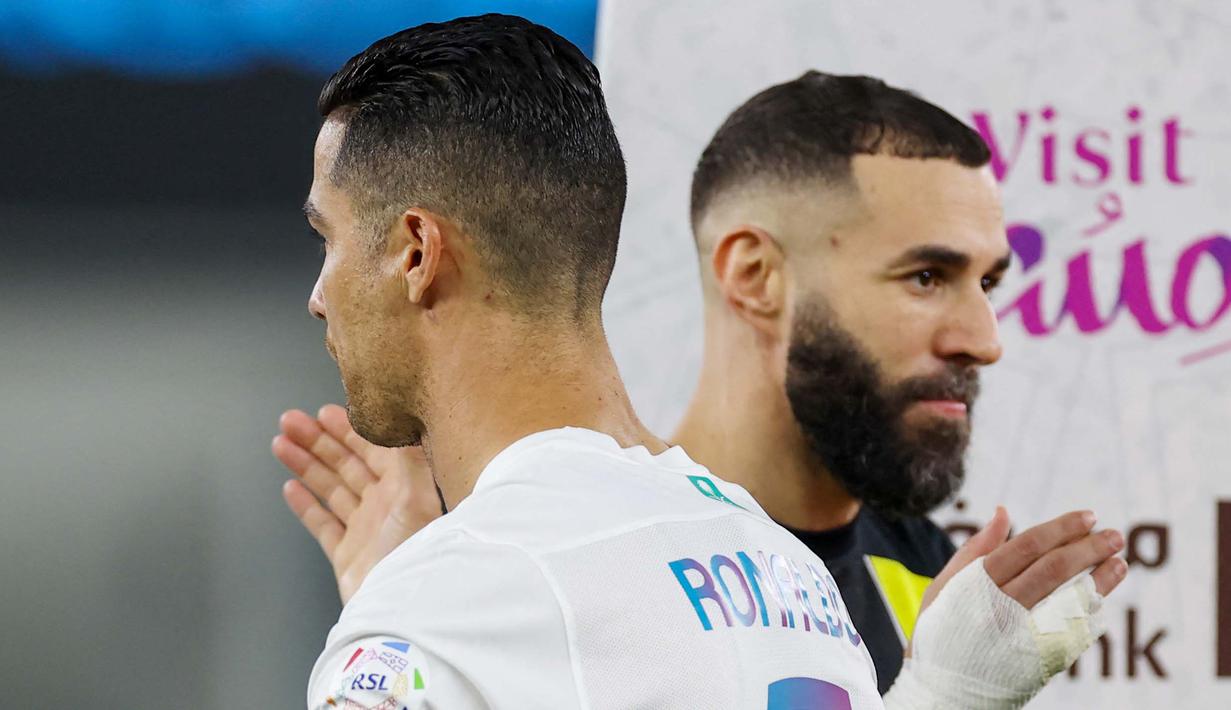 Pemain Al Nassr, Cristiano Ronaldo, berpapasan dengan pemain Al Ittihad, Karim Benzema, dalam laga tunda pekan ke-17 Liga Arab Saudi di King Abdullah Sport City Stadium, Jeddah, Rabu (27/12/2023). Al Nassr menang dengan skor 5-2. (Photo by AFP)