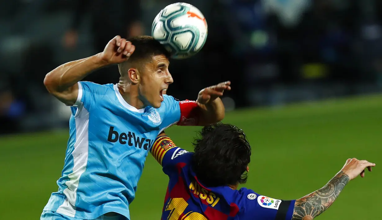 Striker Barcelona, Lionel Messi, duel udara dengan pemain Leganes, Unai Bustinza, pada laga La Liga di Stadion Camp Nou, Selasa (16/6/2020). Barcelona menang 2-0 atas Leganes. (AP Photo/Joan Montfort)