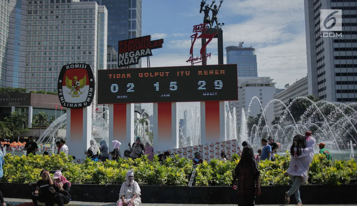 Warga berfoto di depan papan hitung mundur pelaksanaan Pemilu sebagai bagian dari sosialisasi di Bundara HI, Jakarta, Minggu (14/4). Papan tersebut dipasang bertujuan untuk mengingatkan sekaligus mengajak masyarakat untuk mengawasi proses demokrasi terbesar di Indonesia. (Liputan6.com/Faizal Fanani)