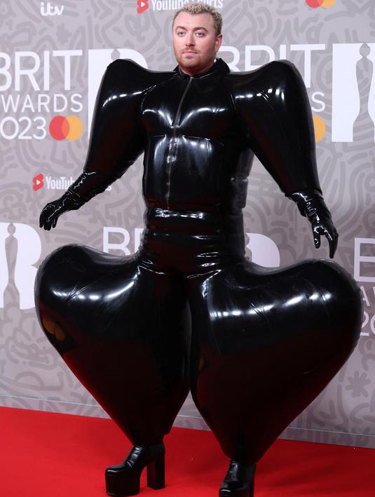 Penyanyi Inggris Sam Smith berpose pada karpet merah Brit Awards 2023 di London, Sabtu (11/2/2023). Gaun berbahan latex itu juga mengkilap dan semakin membuatnya terlihat unik. (Photo by ISABEL INFANTES / AFP)