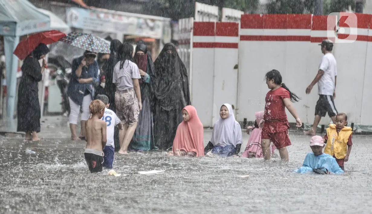 Anak-anak saat bermain di tengah banjir yang merendam Jalan Abdullah Syafei, Tebet, Jakarta, Kamis (18/2/2021). Menurut warga setempat, banjir ini merupakan yang pertama kali terjadi yang diduga disebabkan adanya proyek revitalisasi kolong flyover. (merdeka.com/Iqbal S Nugroho)