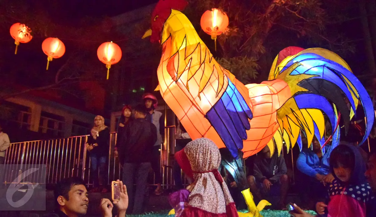 Seorang bocah berpose di dekat lampion berbentuk ayam di kawasan Pasar Gedhe Surakarta saat perayaan Imlek, Surakarta, Sabtu (28/01). Grebeg Soediro adalah  tradisi  tahunan alkuturasi  budaya  Jawa dan  Cina. (Liputan6.com/Gholib)  