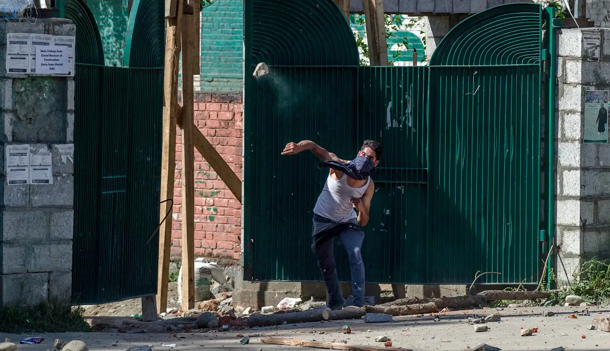 Mahasiswa Kashmir melemparkan batu ke polisi India di Srinagar, Kashmir yang dikuasai India, (23/5). Bentrokan telah meningkat setelah tentara menggerebek sebuah perguruan tinggi di kota selatan Pulwama bulan lalu. (AP Photo/Dar Yasin)