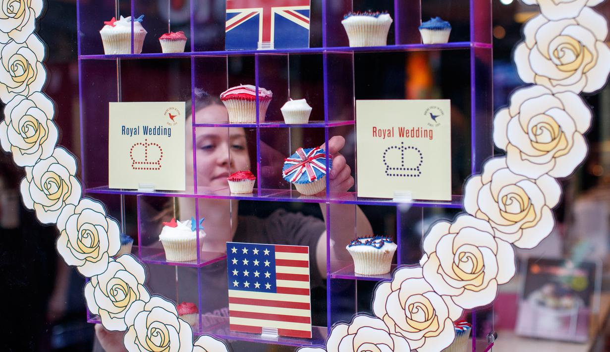 Karyawan menata cupcakes edisi khusus untuk menghormati pernikahan Pangeran Harry dan Meghan Markle di Hummingbird Bakery, London, 11 Mei 2018. Pernikahan Harry dan Meghan digelar 19 Mei mendatang di Kapel St. George, Istana Windsor. (AFP/Tolga AKMEN)