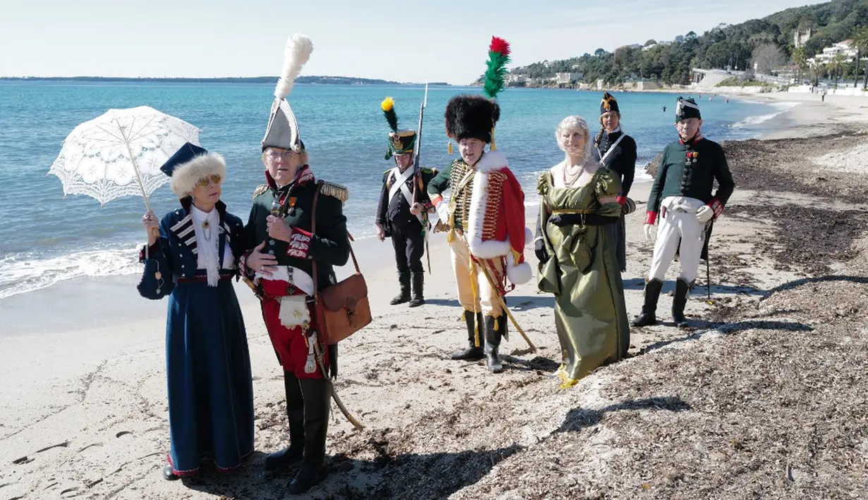 Orang-orang yang mengenakan kostum era Napoleon Bonaparte berjalan di pantai dalam rangka peringatan 200 tahun kematian Napoleon Bonaparte di Saint-Helene, Golfe-Juan, Prancis, 16 Maret 2021. Kaisar Napoleon Bonaparte hidup pada 15 Agustus 1769 hingga 5 Mei 1821. (Valery HACHE/AFP)