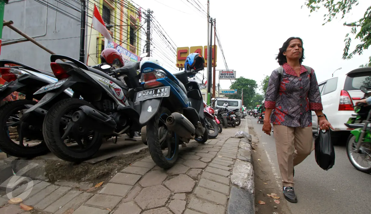 Warga melintas di samping trotoar yang dijadikan tempat parkir motor di Jalan Juanda, Bekasi, 4 Oktober 2016. Trotoar yang seharusnya untuk pejalan kaki ini dialih fungsikan oleh jasa parkir liar sebagai tempat parkir kendaraan bermotor. (Foto: Fajar)