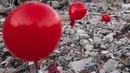 Balon yang tergantung di puing-puing bangunan yang runtuh di Antakya, Turki selatan, menyusul gempa berkekuatan 6,4 yang melanda pada 20 Februari, dua minggu setelah gempa berkekuatan 7,8 melanda dekat Gaziantep dan telah menewaskan lebih dari 44.000 orang.  Di sisi jalan yang sibuk di Antakya, puluhan balon merah berkibar, bergelantungan di reruntuhan.  (AFP/Sameer Al-Doumy)