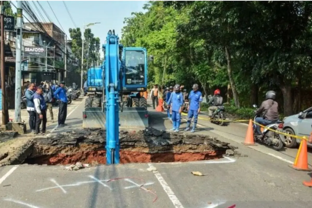 Pekerja Dinas Sumber Daya Air (SDA) Jakarta Selatan menggunakan alat berat untuk memperbaiki jalan ambles di Jalan Raya Lenteng Agung.