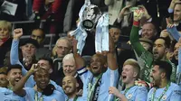 Kapten Manchester City, Vincent Kompany, mengangkat trofi Piala Liga usai mengalahkan Arsenal di Stadion Wembley, London, Minggu (25/2/2018). City menang 3-0 atas Arsenal. (AFP/Glyn Kirk)