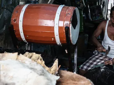Ridho (52) memasang pengikat untuk membuat bedug di kawasan, Tanah Abang, Jakarta, (17/6). Menjelang lebaran, sejumlah pedagang menjual aneka ragam bedug yang dijual dari harga Rp. 100 ribu hingga Rp 4 juta. (Liputan6.com/Faizal Fanani)