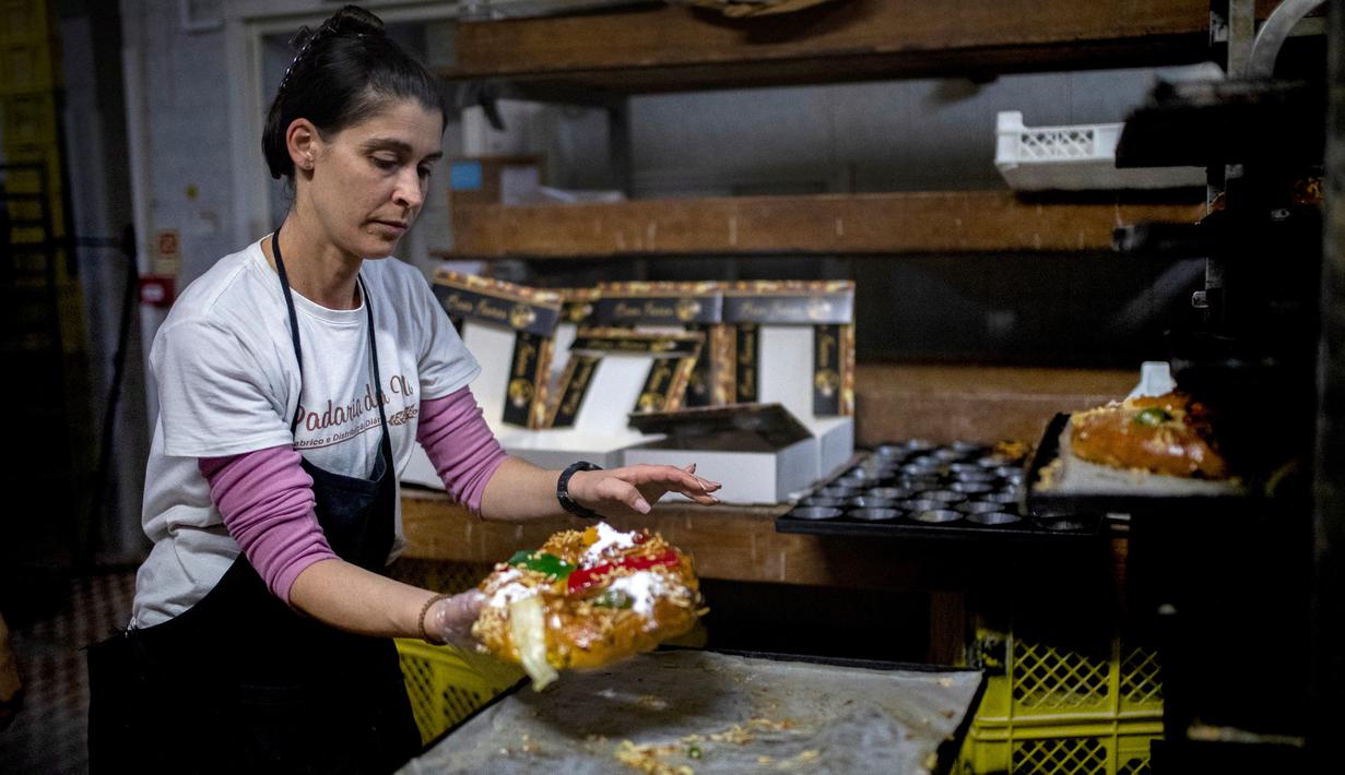 Seorang tukang roti membuat Bolo Rei atau Kue Raja di toko roti Padaria da Ne, Amadora, Portugal, 16 Desember 2022. Bolo Rei disebut sebagai Kue Raja karena bahan-bahan yang dibutuhkan untuk membuat kue ini cukup mahal. (CARLOS COSTA/AFP)