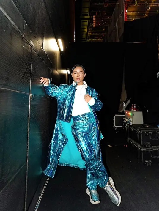 Melihat gaya totalitas Betrand saat manggung. Di sini ia tampil berbeda dengan atasan kaus putih, ditumpuknya dengan outerwear mengkilap bernuansa biru laut dan celana panjang yang serasi. Yang menarik untuk disimak adalah gaya rambut dan makeup totalitas Betrand. Foto: Instagram.