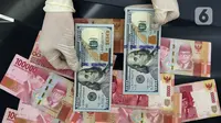 Karyawan menunjukkan uang dolar AS dan rupiah di Jakarta, Rabu (30/12/2020). Nilai tukar rupiah di pasar spot ditutup menguat 80 poin atau 0,57 persen ke level Rp 14.050 per dolar AS. (Liputan6.com/Johan Tallo)