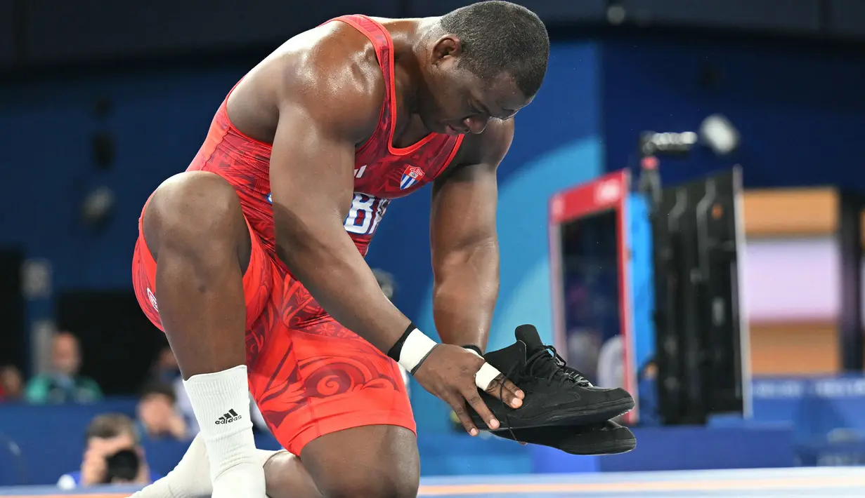Lopez meletakkan sepatunya di tengah matras selepas memenangi final gulat Olimpiade 2024. Gestur itu melambangkan pengunduran dirinya sebagai atlet dan bersiap menggembleng para penerusnya. (AFP/Punit Paranjpe)