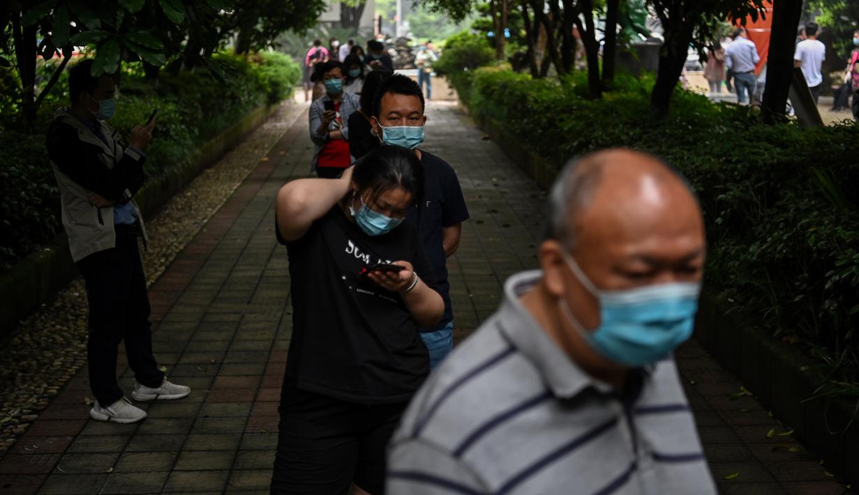 Warga mengenakan masker menunggu dalam barisan untuk tes virus corona di lingkungan di Wuhan, provinsi Hubei, Jumat (15/5/2020). Tes massal yang ditargetkan dalam 10 hari ini akibat adanya pasien Virus Corona baru di Wuhan, setelah sebulan lebih tidak ada laporan kasus baru. (Hector RETAMAL/AFP)