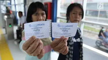 Penumpang menunjukkan tiket sebelum menjajal layanan bus Transjakarta koridor 13 rute Tendean-Ciledug, Jakarta, Minggu (13/8). Hari ini, PT Transjakarta menggratiskan layanan bus Transjakarta yang baru dalam tahap uji coba. (Liputan6.com/Herman Zakharia)