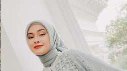 Caitlin Halderman tak kalah anggun dengan hijab pashmina biru pastel yang elegan. Ia mengenakan gaun panjang bertekstur lace dengan motif geometris dan detail sulaman bintang putih yang memberi kesan mewah. Pilihan busana Caitlin memancarkan aura elegan, rapi, dan sangat menawan. (Liputan6.com/IG/@caitlinhalderman)