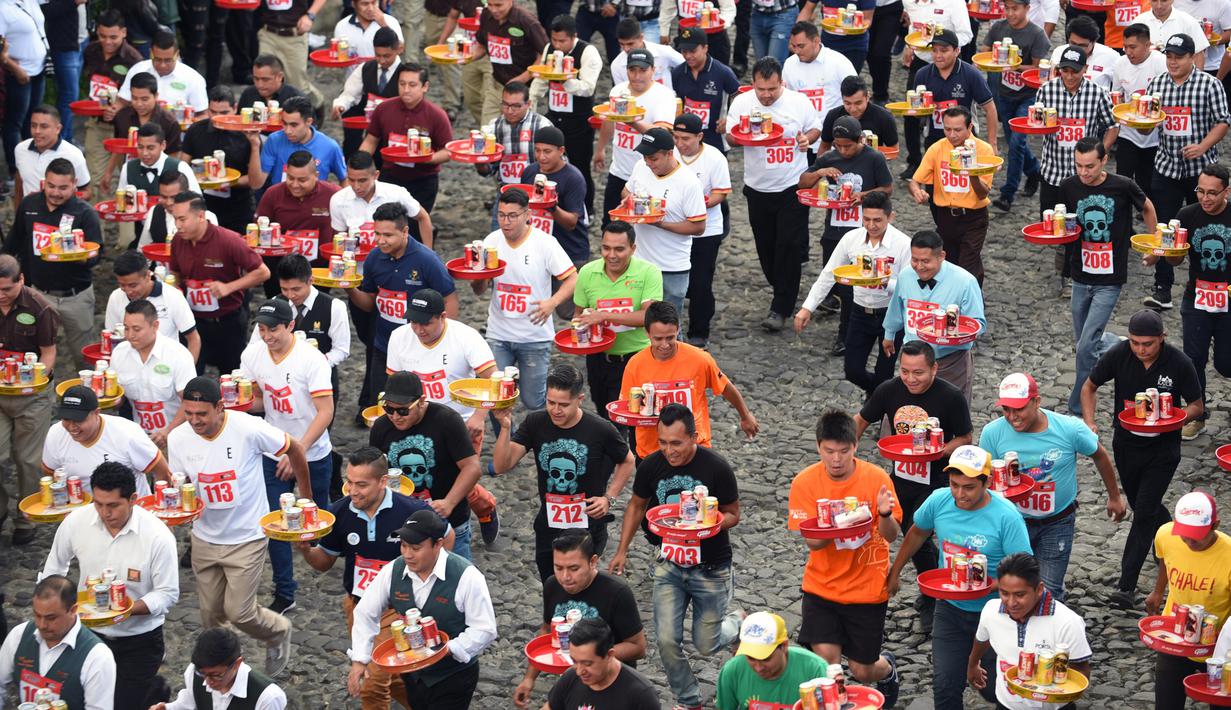 Pramusaji dari berbagai restoran berpartisipasi dalam Waiters Race ke-16 di Antigua, barat daya Ibu Kota Guatemala City, Rabu (14/11). Ratusan peserta beradu kecepatan sembari membawa nampan berisi dua minuman ringan, bir dan air. (JOHAN ORDONEZ/AFP)