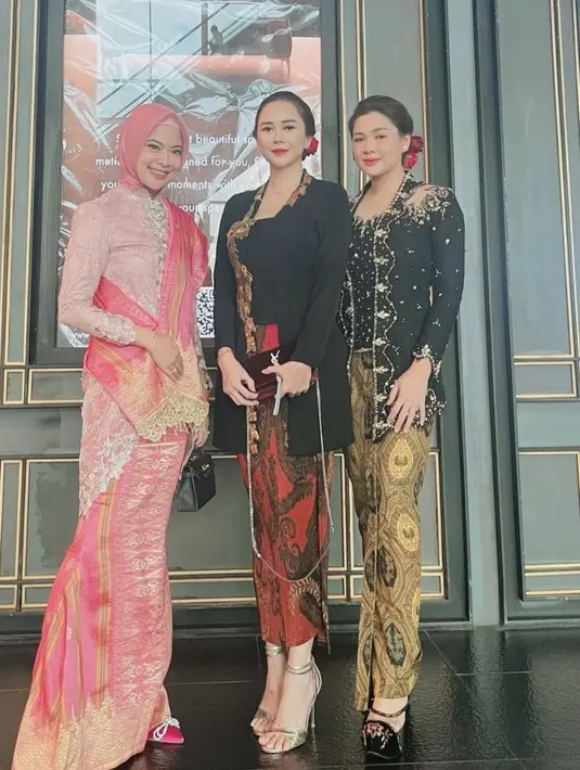 Kebaya hitam tersebut dipadukan kain lilit batik merah, yang serasi dengan warna sling bag YSLnya. Ia pun mengenakan heels keemasan berfoto di samping Vicky Shu. @sucisuaibsaenong