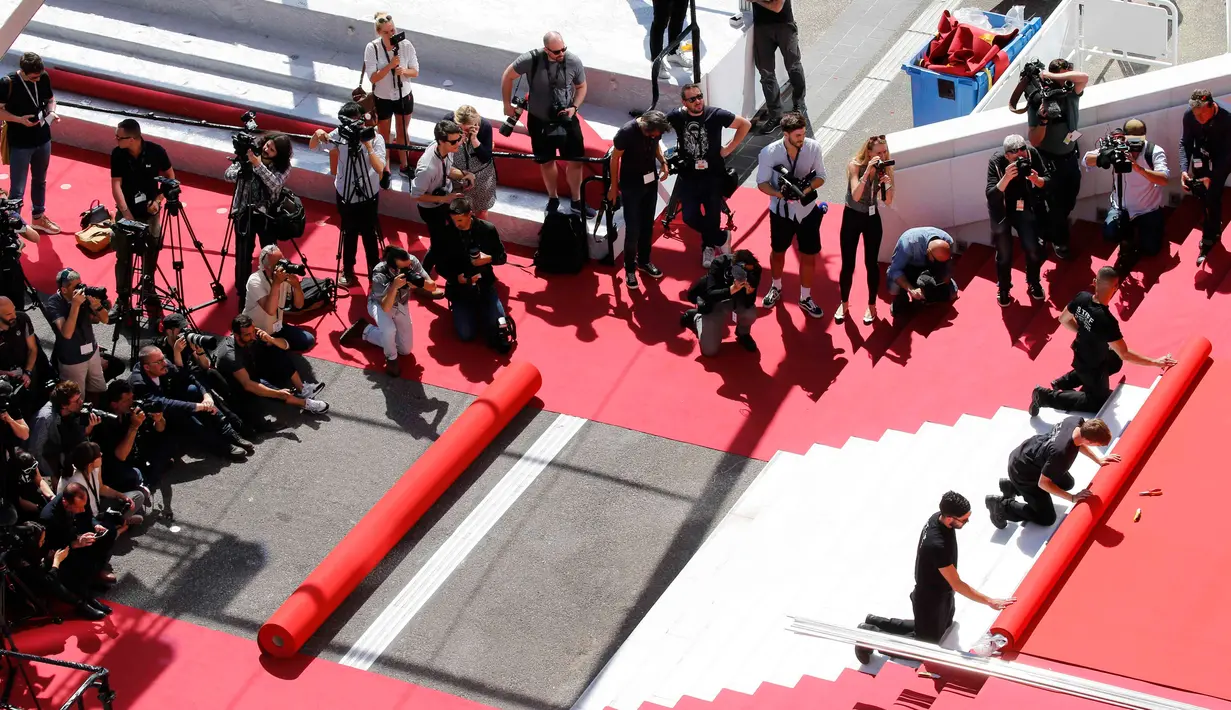 Pekerja memasang karpet merah di depan pintu masuk utama jelang upacara pembukaan Festival Film Cannes 2019 di Cannes, Prancis, Selasa (14/5/2019). Festival Film Cannes 2019 berlangsung pada tanggal 14 hingga 25 Mei. (REUTERS/Stephane Mahe)