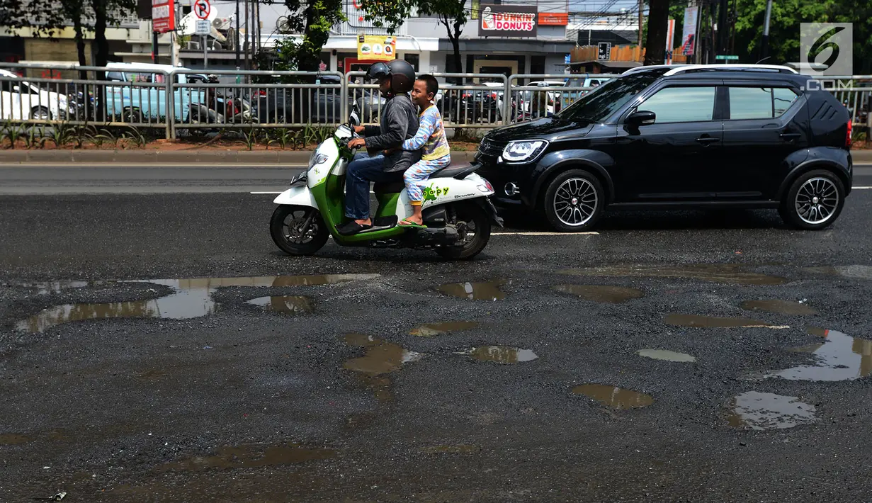 Pengendara mobil dan sepeda motor menghindari jalan yang ruas saat melintasi ruas Jalan Lapangan Ros, Tebet, Jakarta, Sabtu (11/5/2019). Jalan-jalan berlubang yang terisi air tersebut dapat mengakibatkan kecelakaan bagi pengendara kendaraan bermotor. (merdeka.com/Imam Buhori)