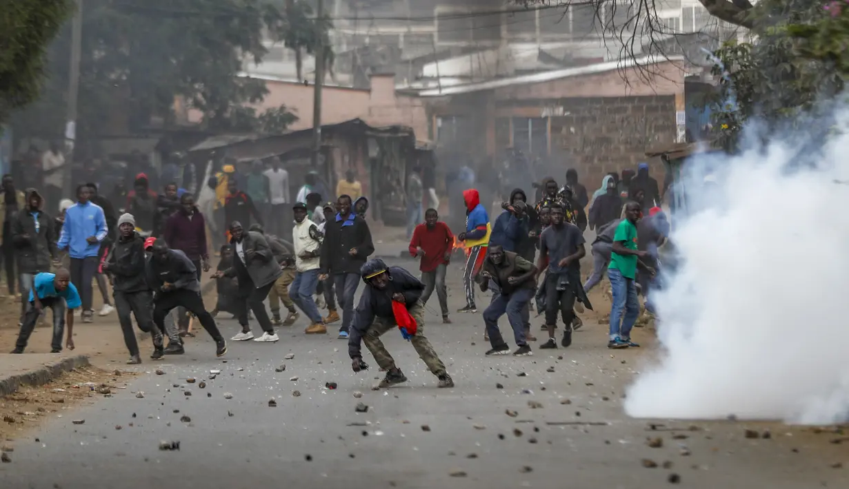 Para pengunjuk rasa melempari polisi dengan batu saat terjadi bentrokan di samping awan gas air mata di daerah Kibera, Nairobi, Kenya, Rabu, 19 Juli 2023. Warga Kenya kembali melakukan protes di jalan-jalan ibu kota Rabu menentang pajak yang baru diberlakukan dan kenaikan biaya hidup.  (AP Photo/Brian Inganga)