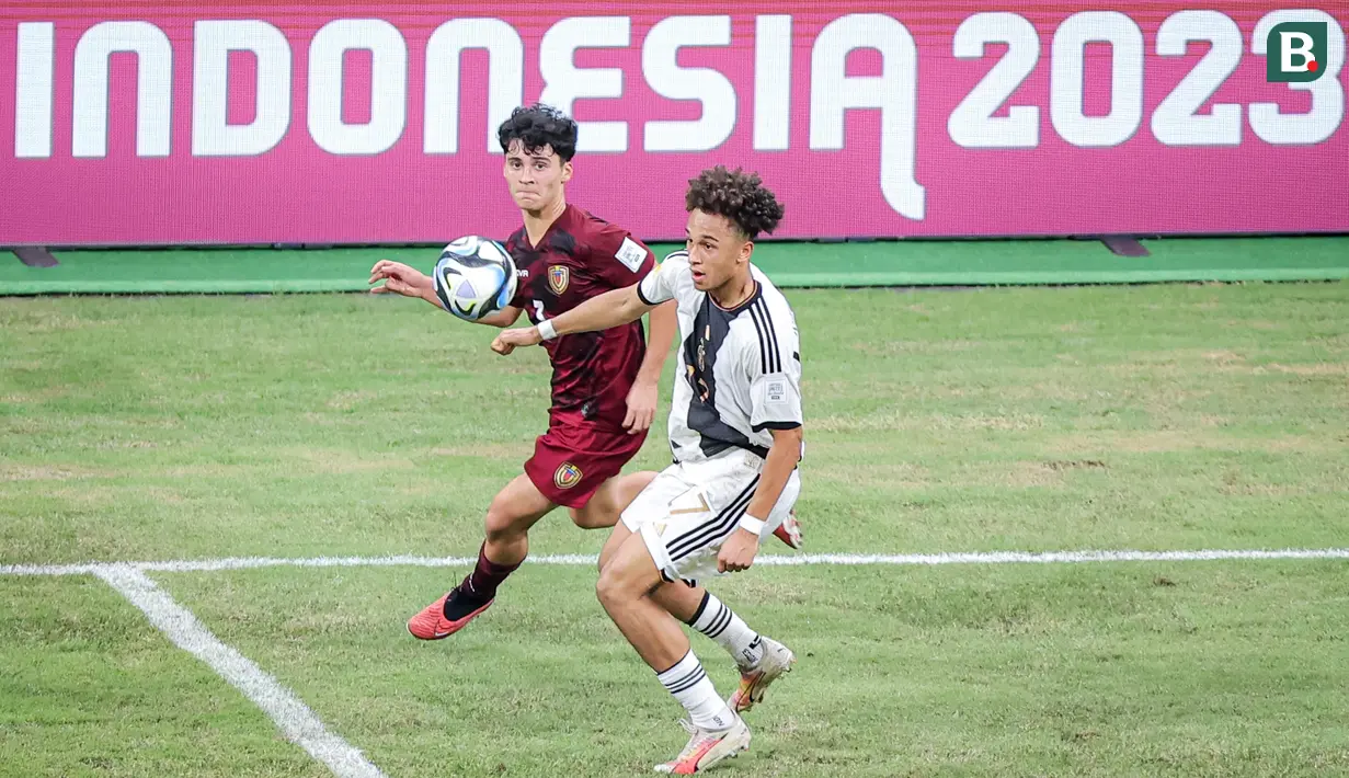 Pemain Timnas Jerman U-17, Eric Emanuel Da Silva Moreira (kanan) berusaha mengontrol bola dibayangi pemain Timnas Venezuela U-17, Santiago Silva, dalam laga pamungkas Grup F Piala Dunia U-17 2023 yang berlangsung di Jakarta International Stadium (JIS), Jakarta, Sabtu (18/11/2023). (Bola.com/Bagaskara Lazuardi)